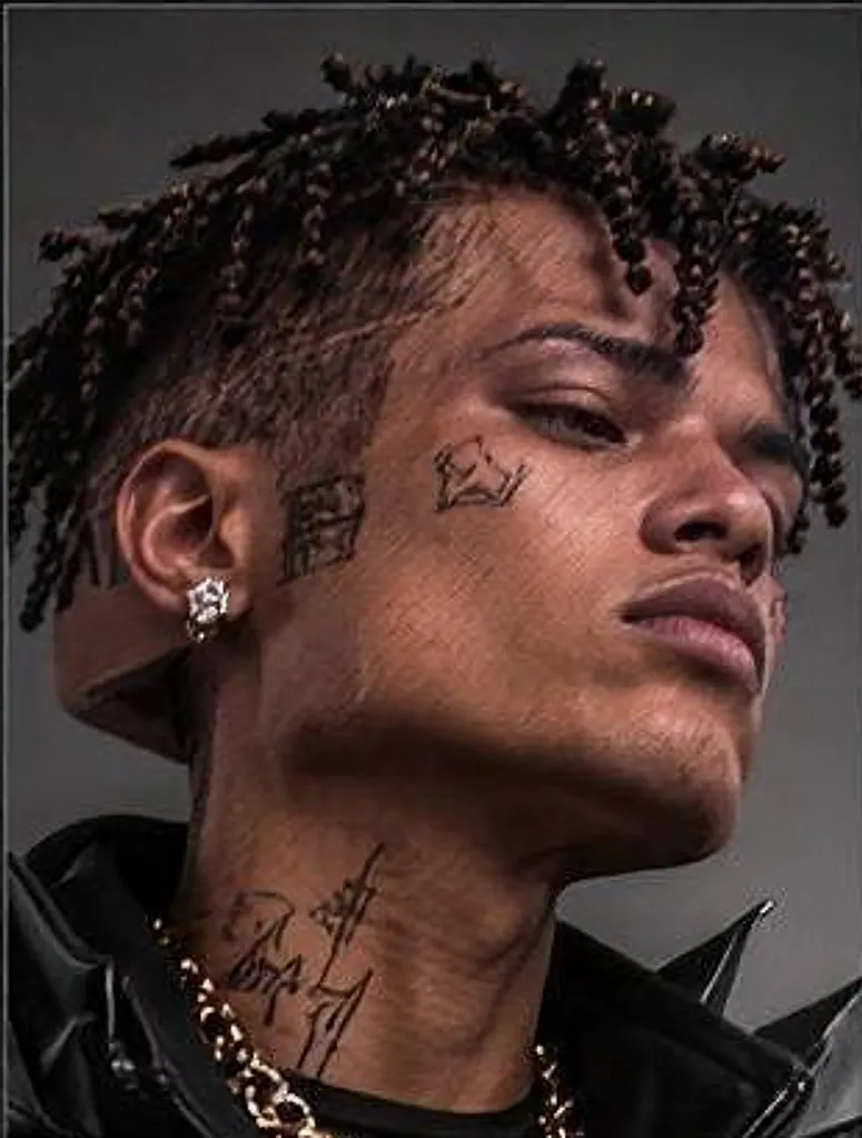Close portrait of KUBE 03 in three-quarter profile, crown tattoo on the cheek